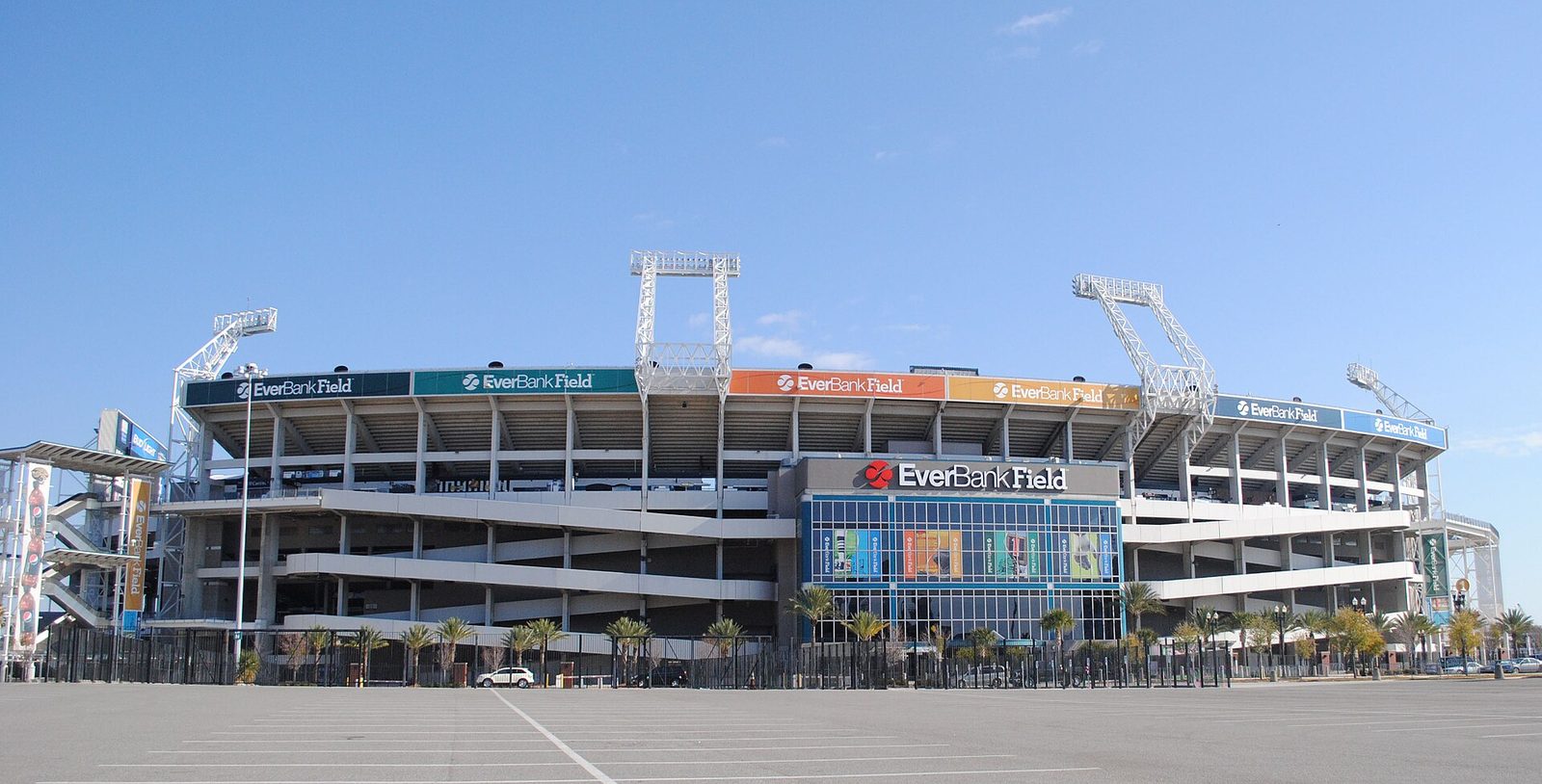 Exterior of the Jacksonville Jaguars stadium with EverBank Field signs above the main entrance and an empty parking lot in front