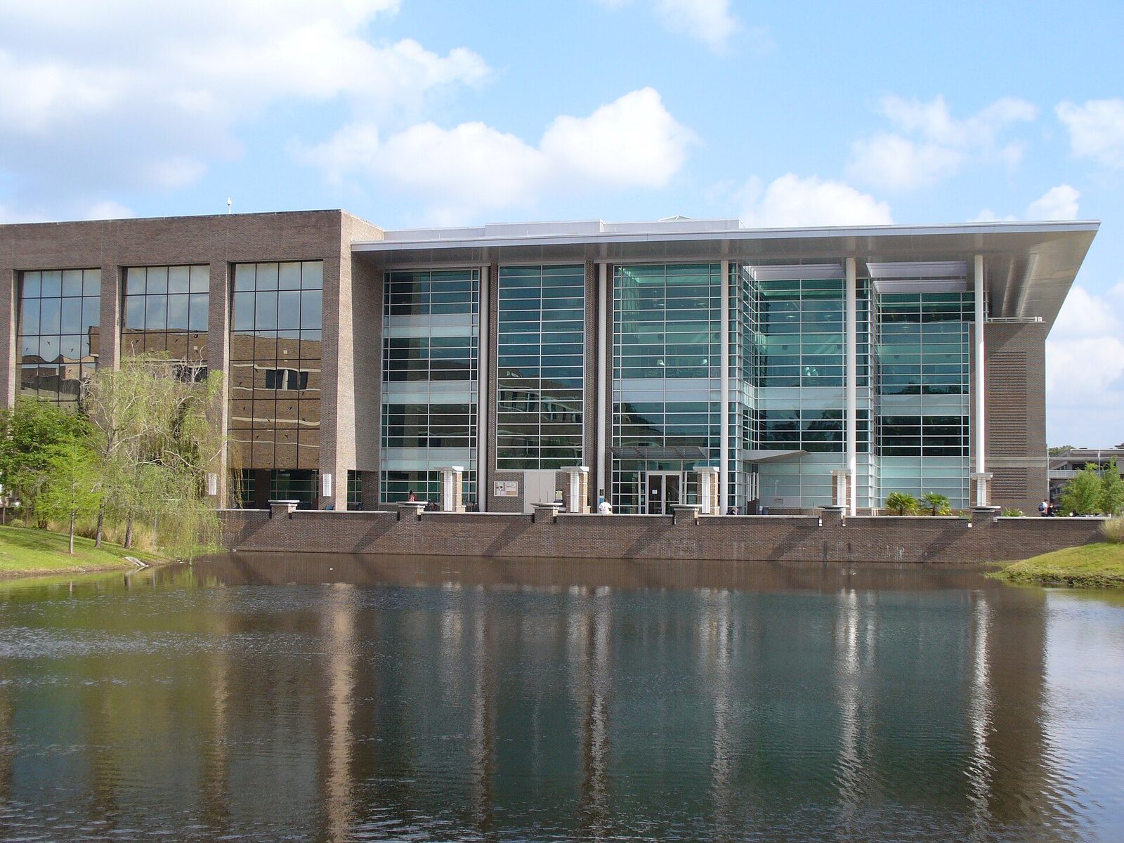 The Thomas G. Carpenter Library at the University of North Florida reflected in a campus lake under a blue sky